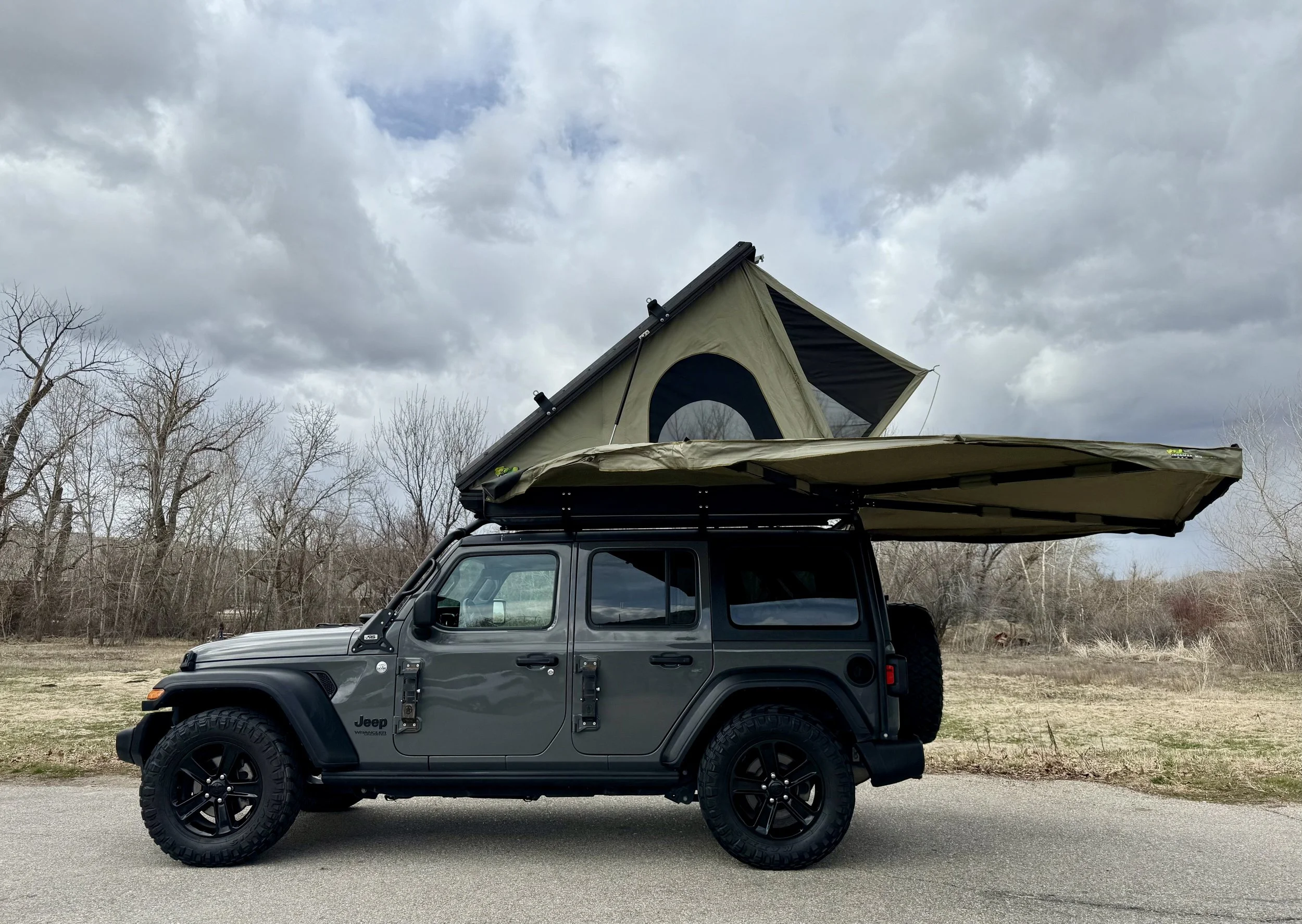 Side profile of the Jeep with hard-shell rooftop tent deployed and 270° awning fully extended