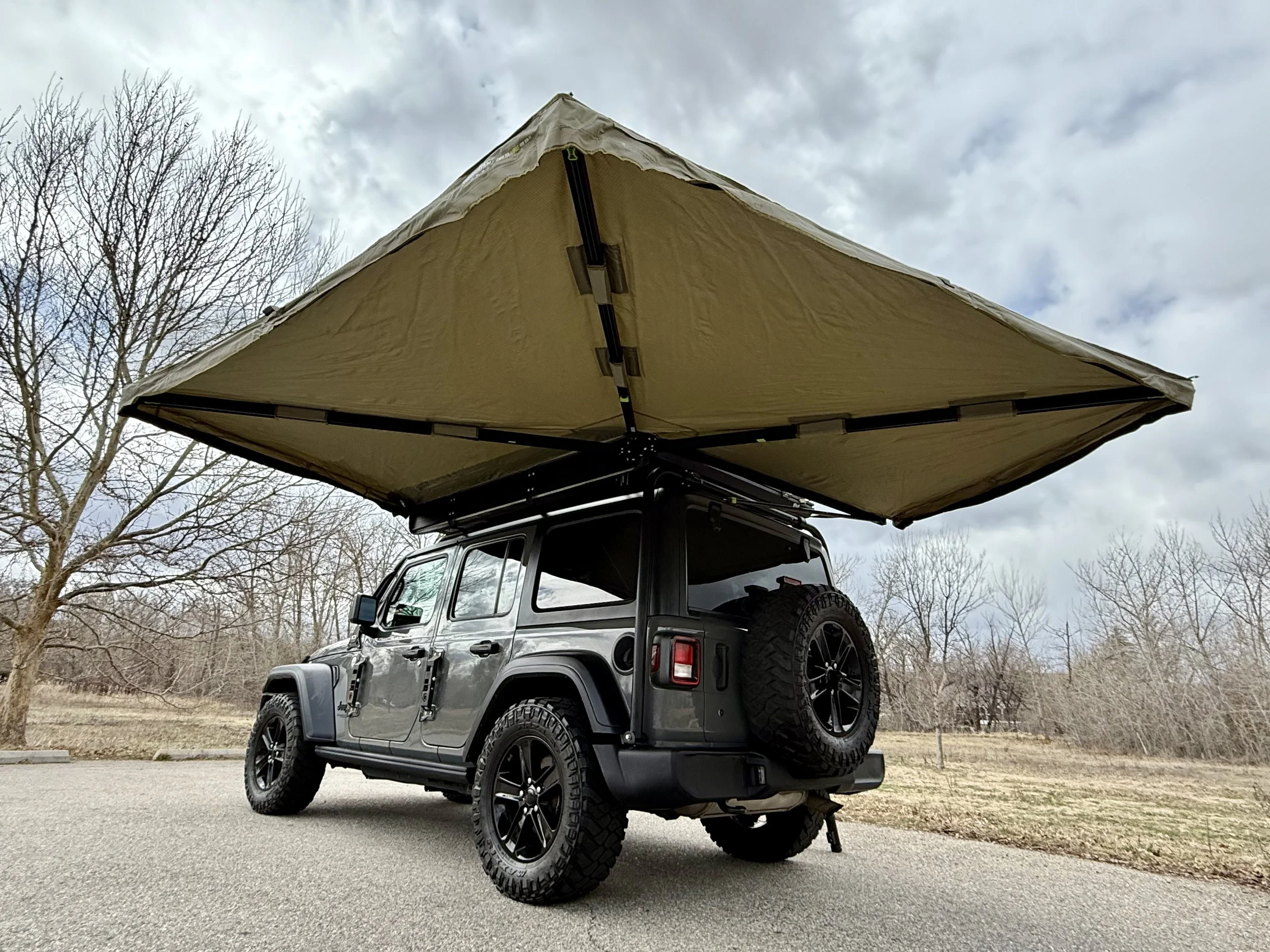 Rear three-quarter view of the Jeep with the full 270° awning completely open for maximum shade and the overland setup visible