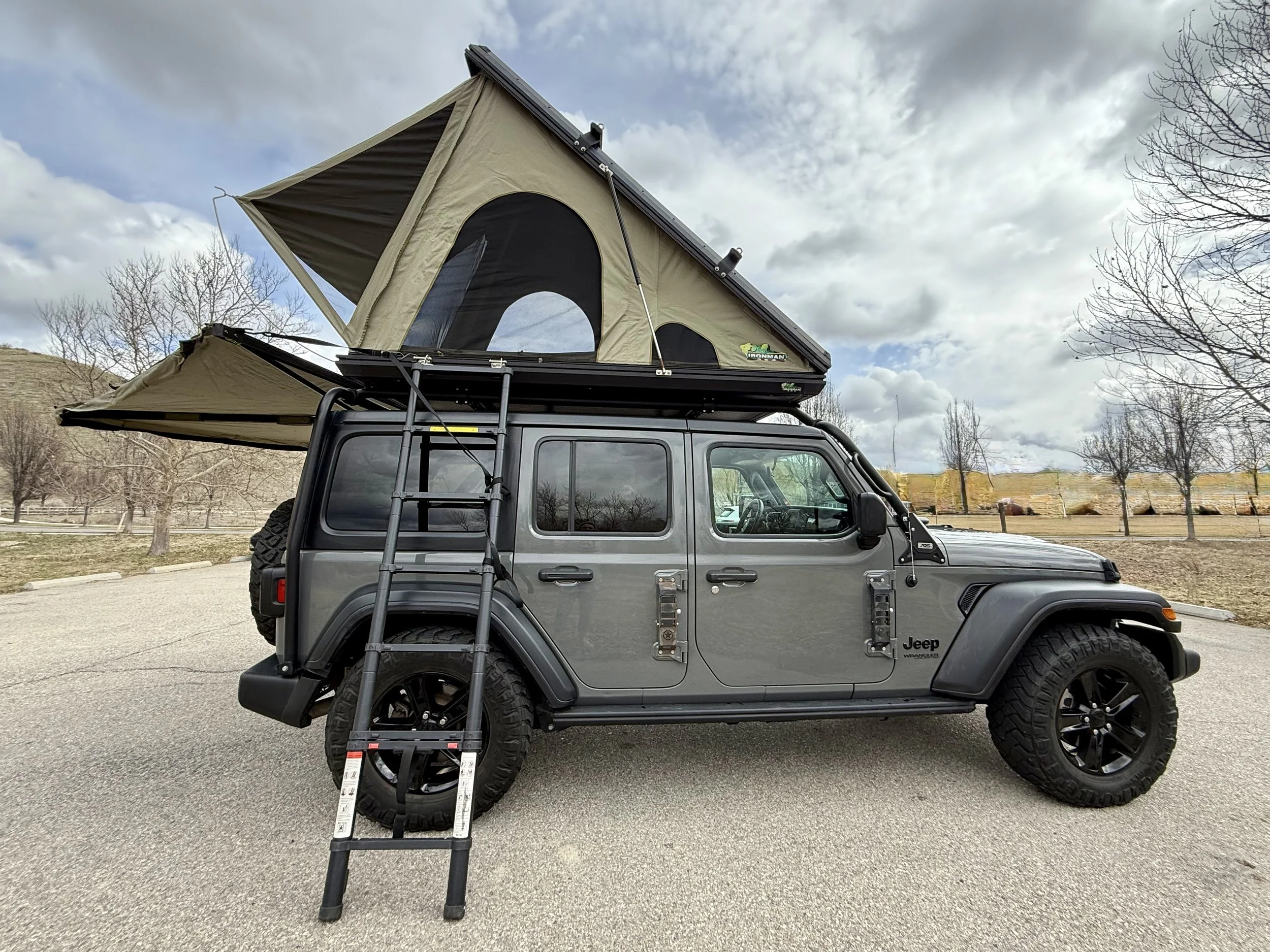 2020 Jeep Wrangler JL fully deployed in overlanding mode with hard-shell rooftop tent open, 270° awning extended, ladder down, and exoskeleton visible